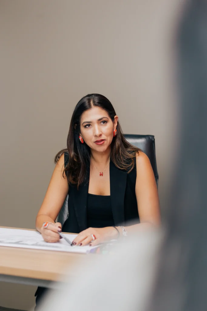 Una mujer sentada en un escritorio escribiendo en un trozo de papel.